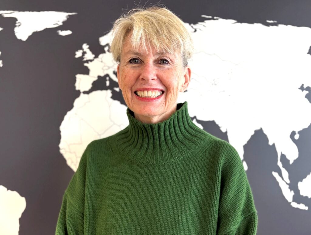 Headshot of Deborah Crowe in front of a world map.