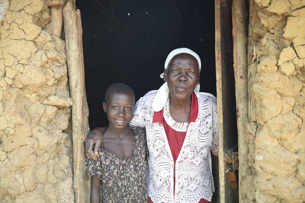 Benedetta standing with her granddaughter at the entrance to a house.