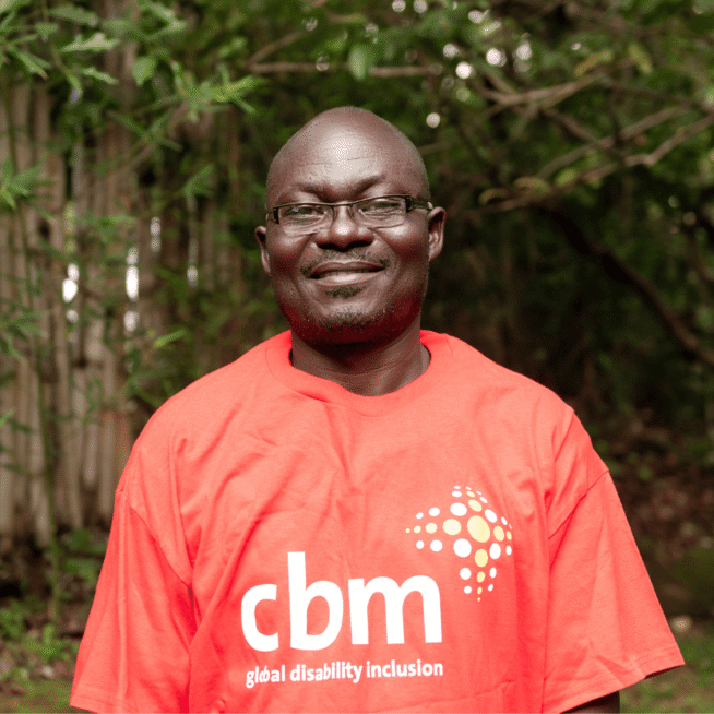 Adrian Sakwa, wearing a CBM t-shirt, smiles at the camera.