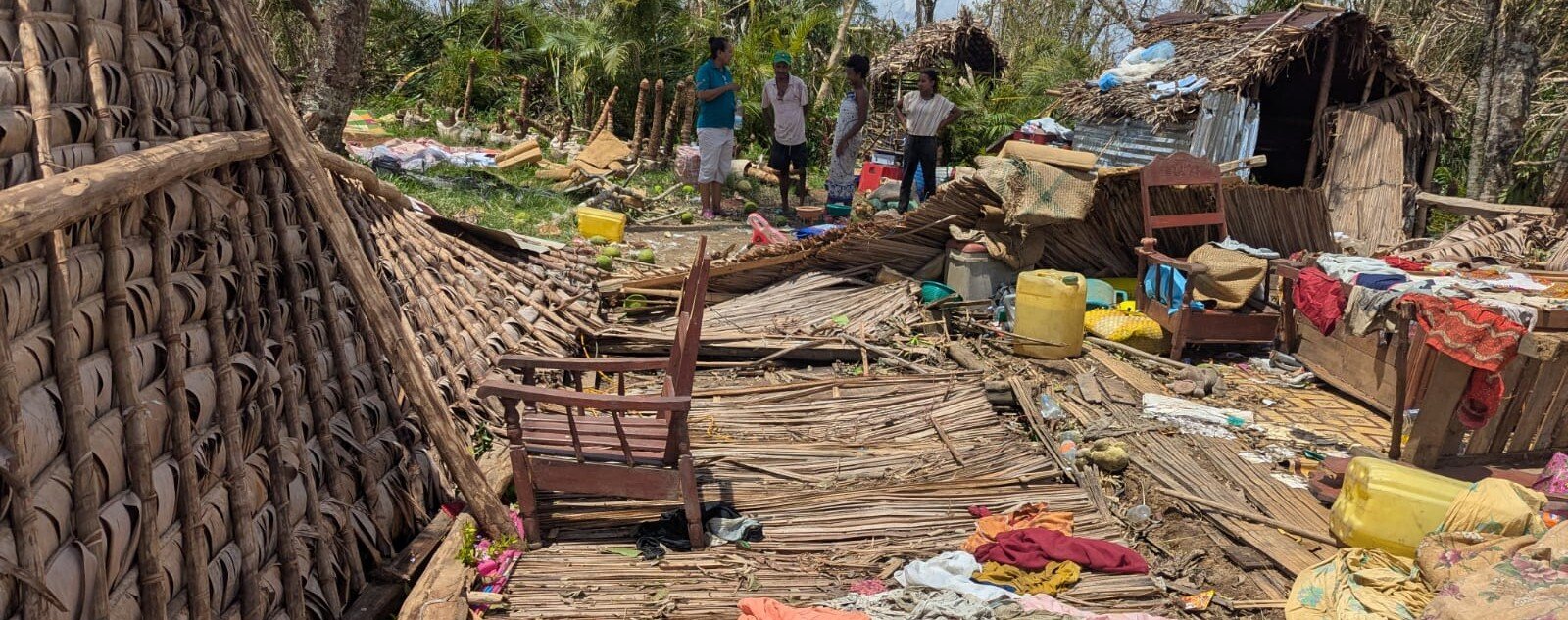 Destroyed huts and household contents strewn across the ground.