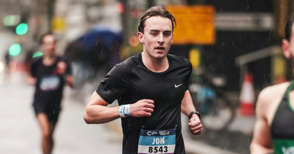 Jon running the London marathon. He is wearing a black running t-shirt.