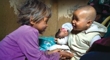 Baby Sombiniaina from Madagascar, smiling with her older sister. Your love can light the way to save sight and even lives.