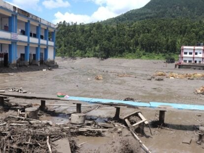 Flood-damaged buildings and muddy sediment covering the ground.